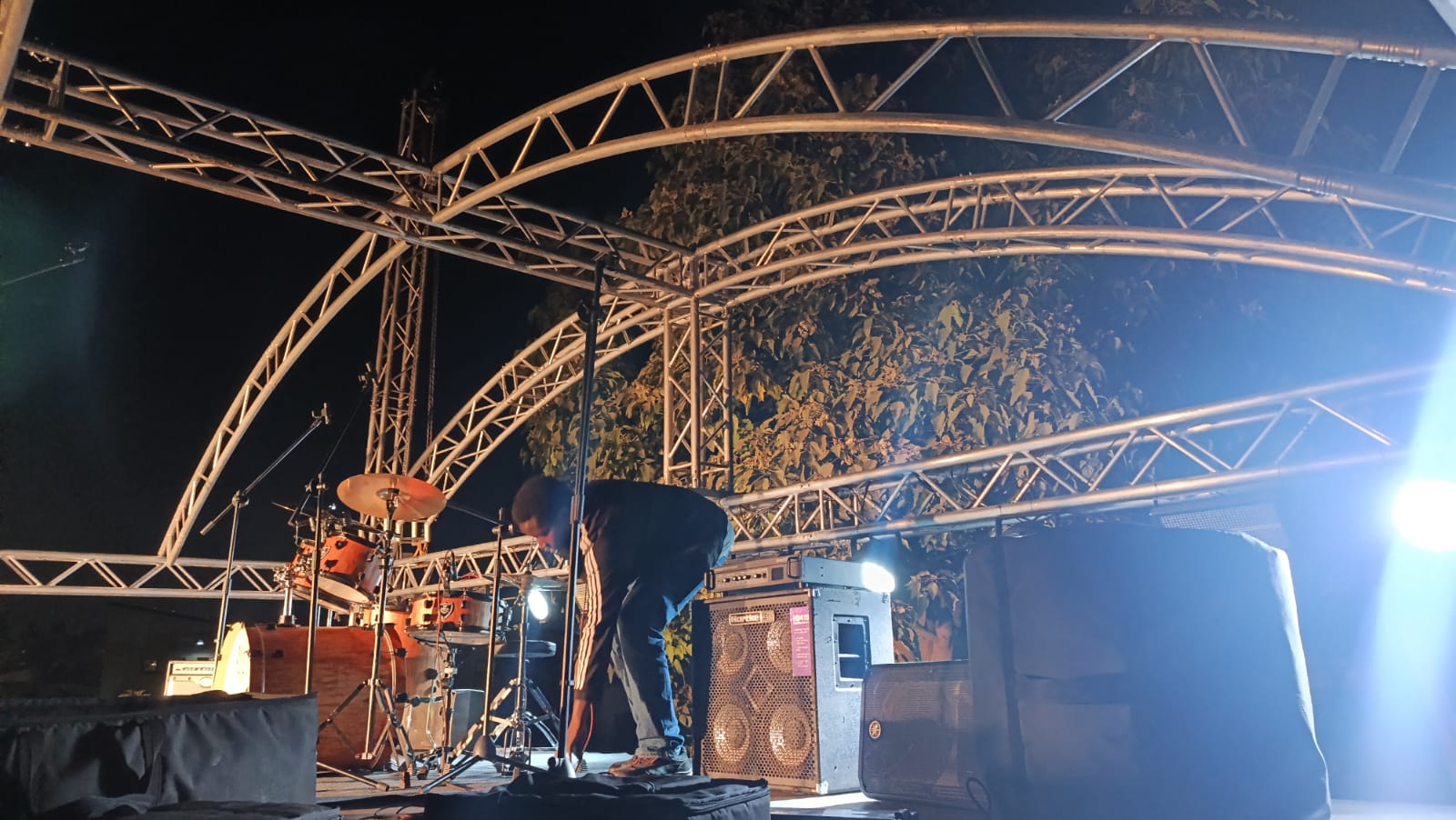 Curved truss arch stage with band backline and lighting at an outdoor night event in Kenya
